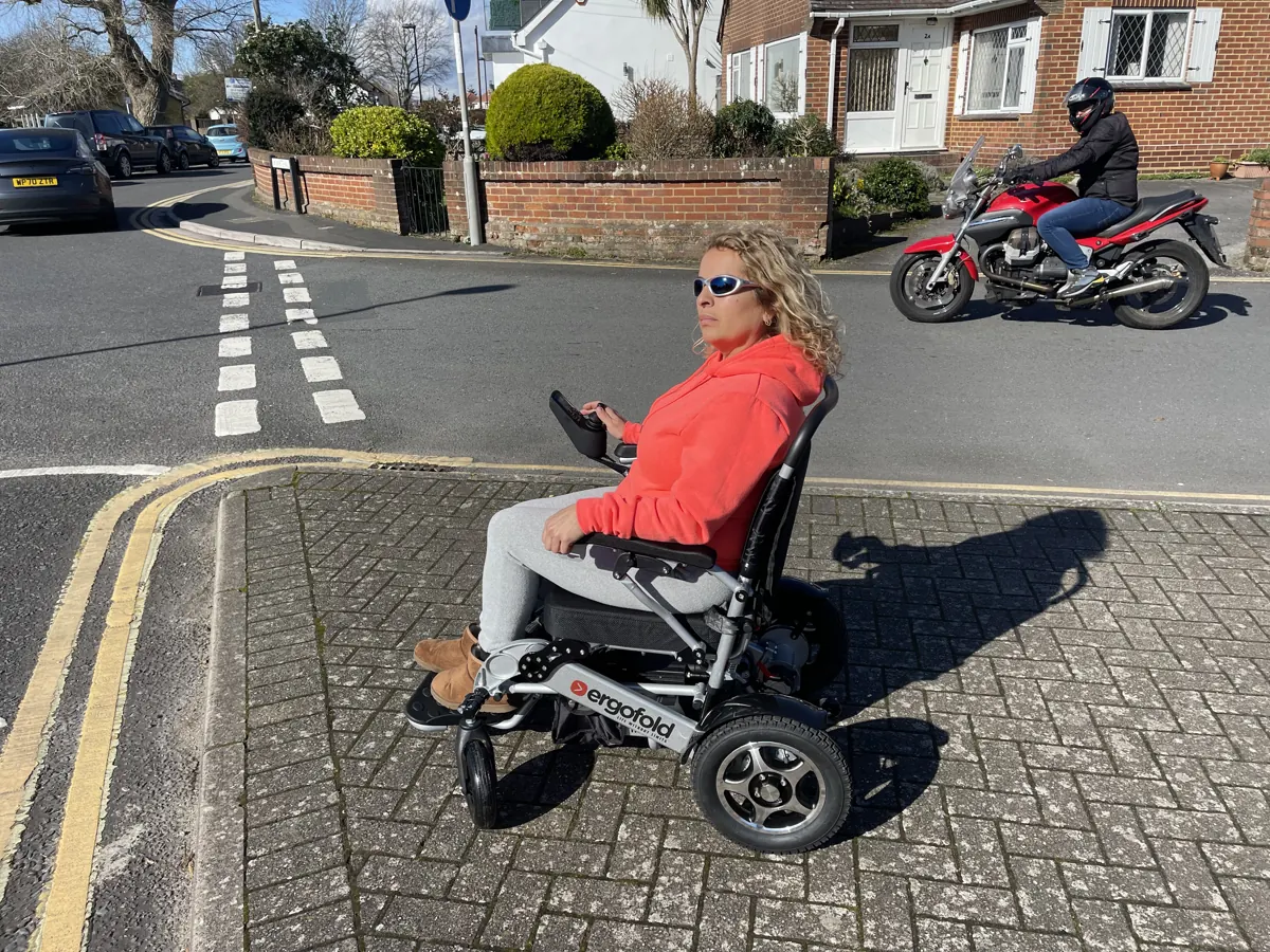 A rider in the ErgoFold Elite on a paved path beside a residential street